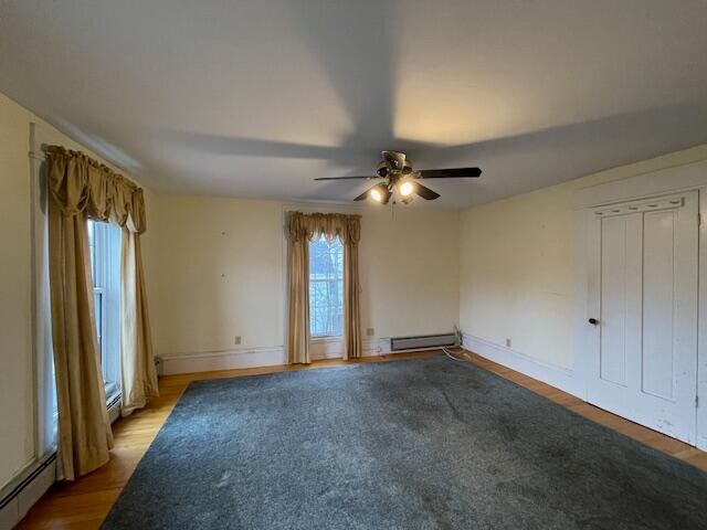 unfurnished room with ceiling fan, light wood-type flooring, and baseboard heating