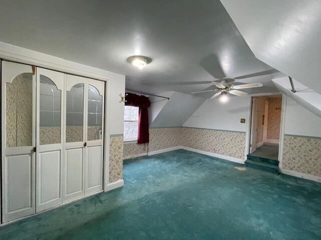 additional living space featuring dark colored carpet, ceiling fan, and vaulted ceiling