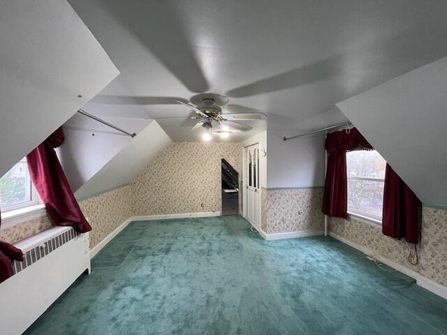 additional living space featuring carpet, ceiling fan, radiator, and vaulted ceiling