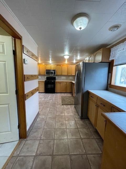 kitchen featuring light tile patterned floors, ornamental molding, and appliances with stainless steel finishes