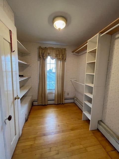 walk in closet with baseboard heating and light hardwood / wood-style flooring