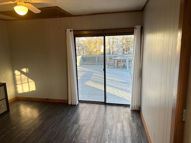 empty room featuring wood walls, dark hardwood / wood-style floors, ceiling fan, and ornamental molding