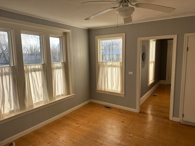 empty room with ceiling fan, ornamental molding, and light wood-type flooring