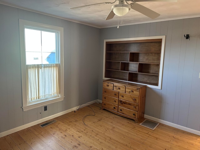 bedroom with wood walls, ceiling fan, light hardwood / wood-style floors, and ornamental molding