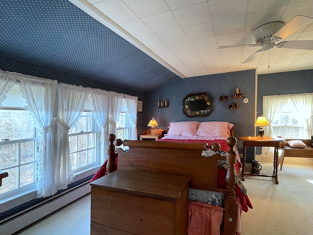 carpeted bedroom with ceiling fan, lofted ceiling, and a baseboard heating unit