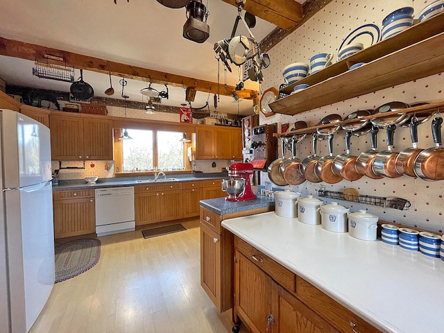 kitchen with beamed ceiling, light wood-type flooring, white appliances, and sink