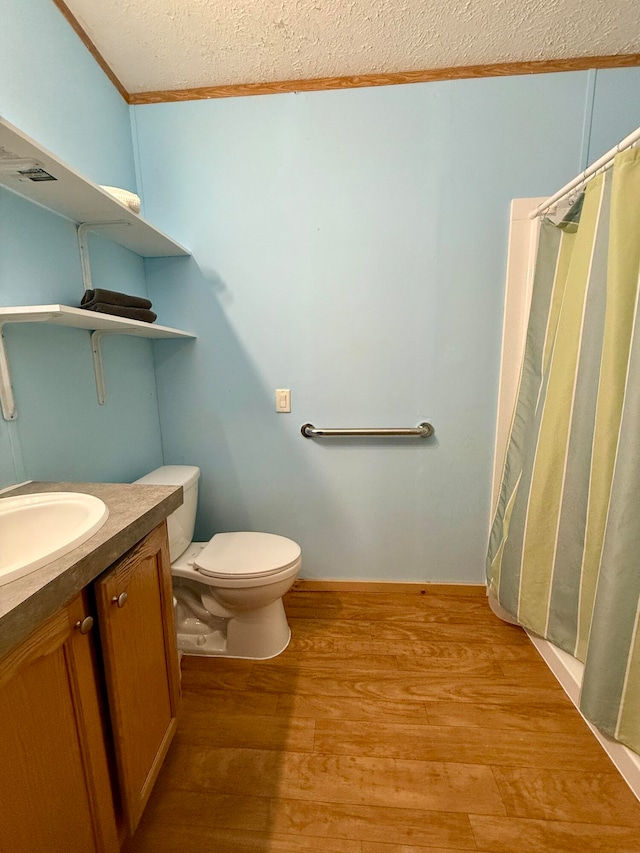 bathroom with vanity, crown molding, toilet, a textured ceiling, and wood-type flooring