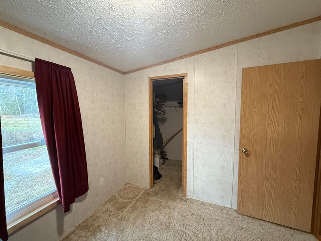 unfurnished room featuring carpet flooring, a textured ceiling, crown molding, and lofted ceiling