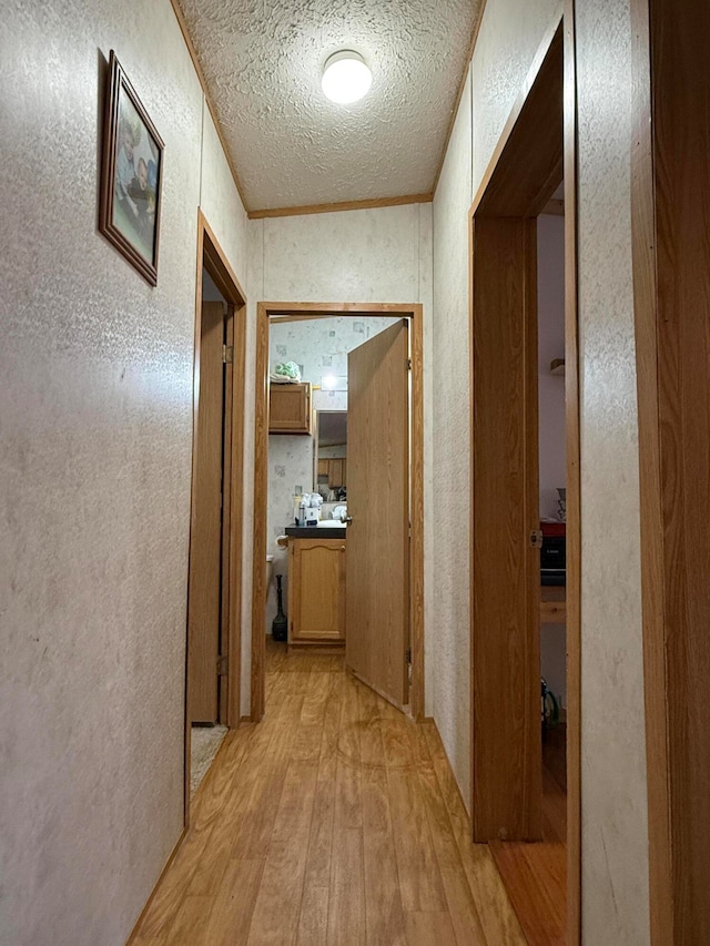 corridor with a textured ceiling and light hardwood / wood-style flooring