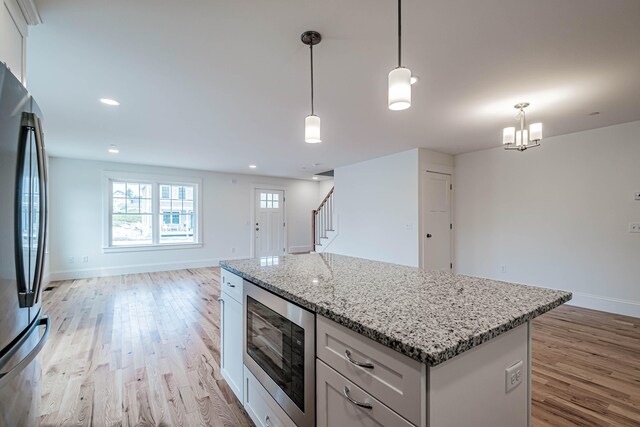 kitchen with hanging light fixtures, an inviting chandelier, light hardwood / wood-style flooring, white cabinets, and appliances with stainless steel finishes