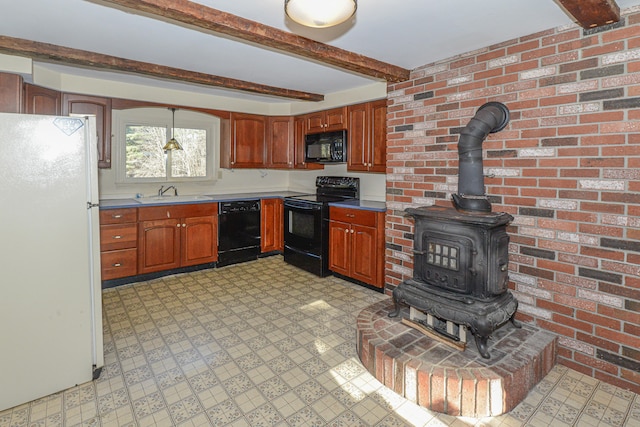 kitchen with beam ceiling, a wood stove, black appliances, and brick wall