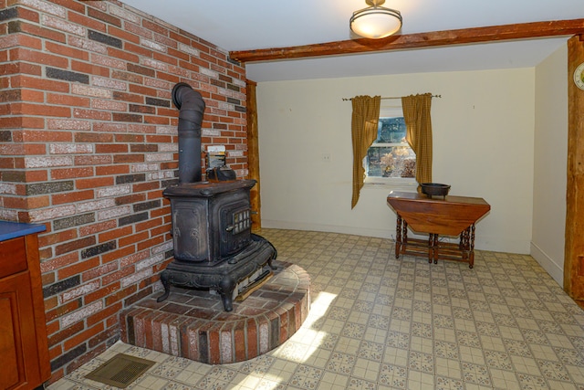 living room with beam ceiling, a wood stove, and brick wall