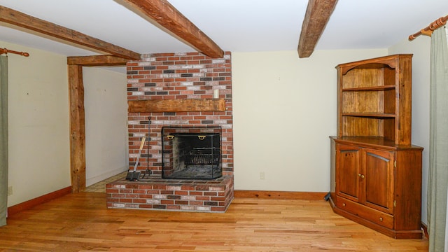 unfurnished living room with a fireplace, light hardwood / wood-style floors, and beamed ceiling