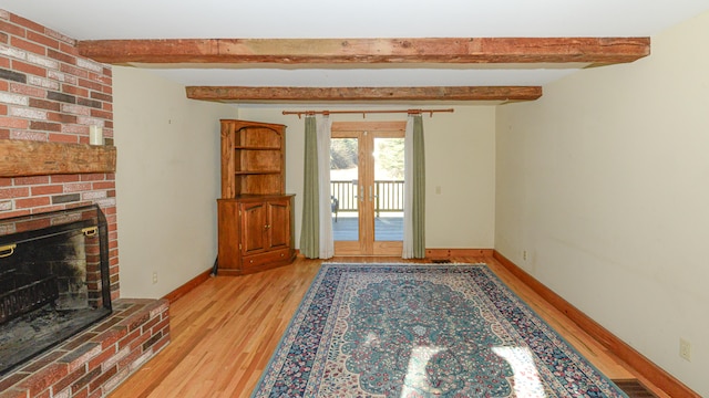 interior space with a fireplace, french doors, light hardwood / wood-style flooring, and beam ceiling