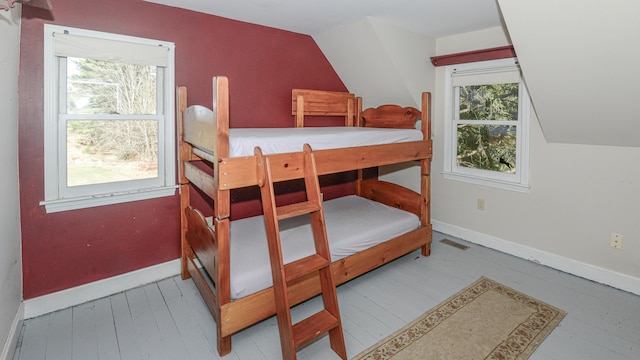 bedroom with light hardwood / wood-style floors, lofted ceiling, and multiple windows