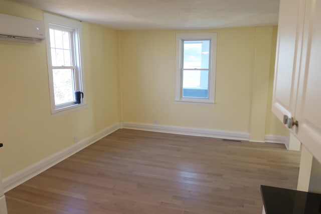 spare room featuring a wall unit AC and light hardwood / wood-style flooring