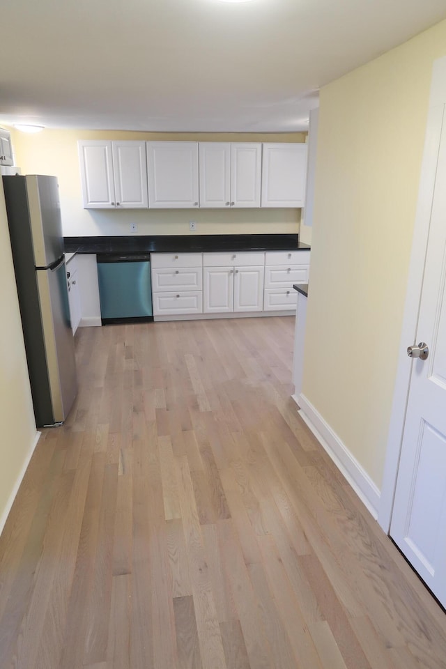 kitchen with white cabinets, light wood-type flooring, and appliances with stainless steel finishes