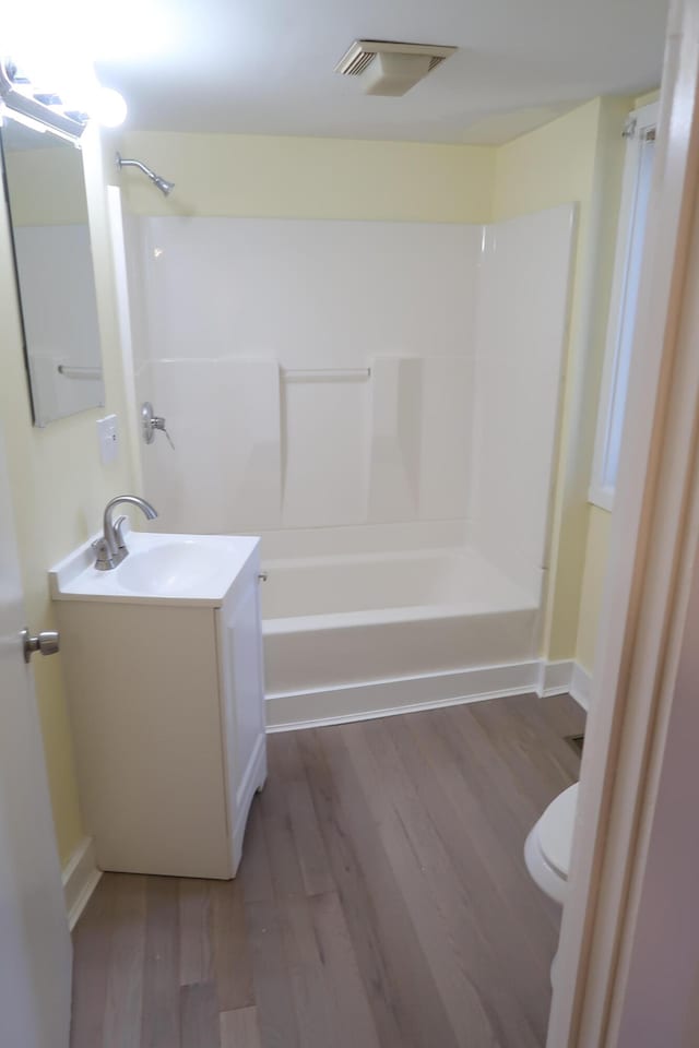 full bathroom with hardwood / wood-style floors, vanity, toilet, and tub / shower combination