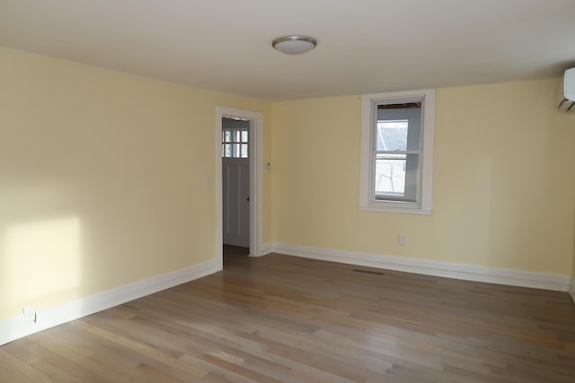 empty room featuring a wall mounted air conditioner and light wood-type flooring