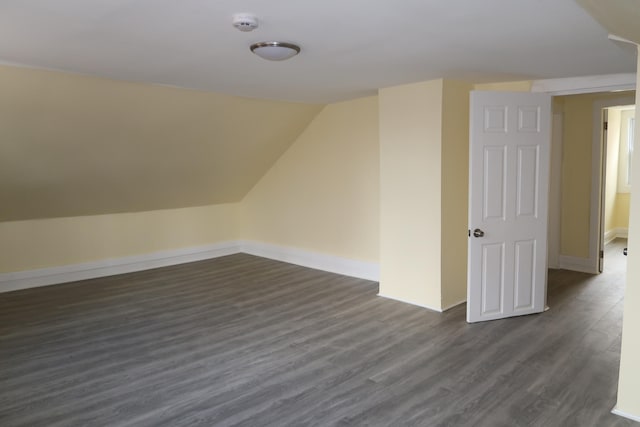 bonus room with dark wood-type flooring and vaulted ceiling