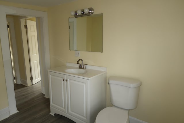 bathroom with toilet, vanity, and hardwood / wood-style flooring