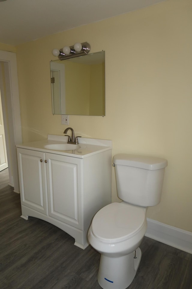 bathroom with toilet, vanity, and hardwood / wood-style flooring