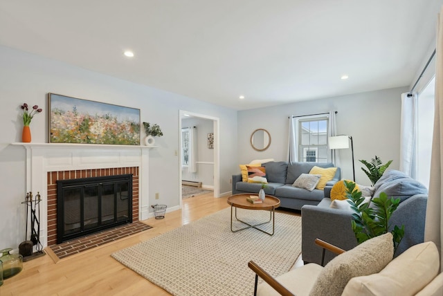 living room featuring a fireplace, light wood-type flooring, and baseboard heating