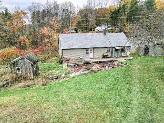 rear view of house featuring a lawn, a wooden deck, and a storage unit