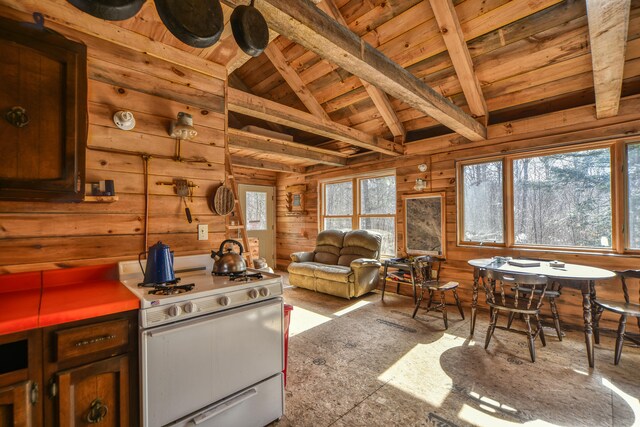 kitchen with lofted ceiling with beams, white range with gas stovetop, wooden walls, and wooden ceiling