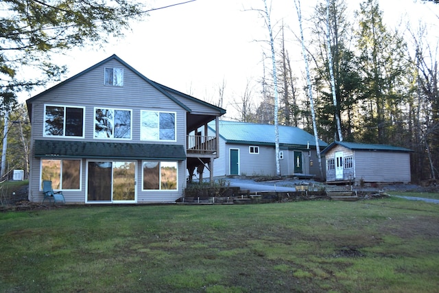 rear view of house with a lawn and a balcony