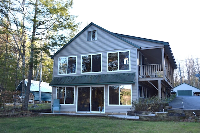 rear view of house featuring a sunroom, a garage, an outdoor structure, and a yard