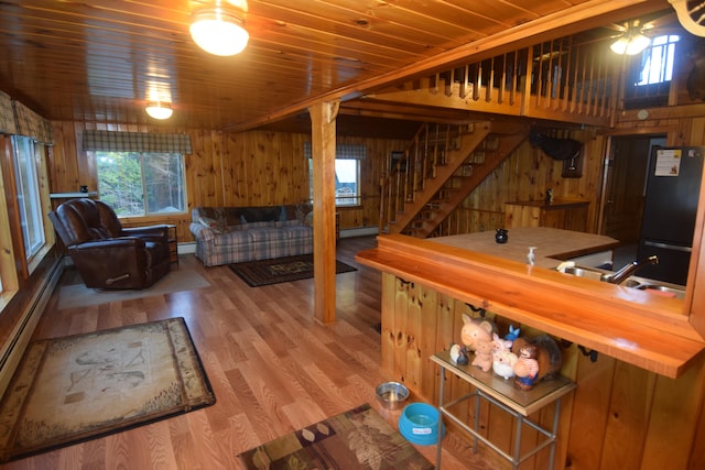 interior space featuring sink, wooden walls, a baseboard radiator, light hardwood / wood-style floors, and wood ceiling