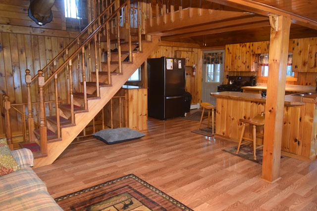 interior space with beamed ceiling, light wood-type flooring, wooden walls, and sink