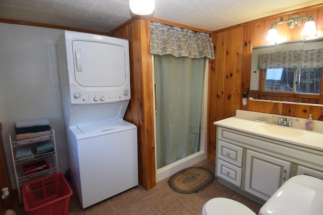 bathroom with vanity, stacked washer / dryer, crown molding, and wood walls