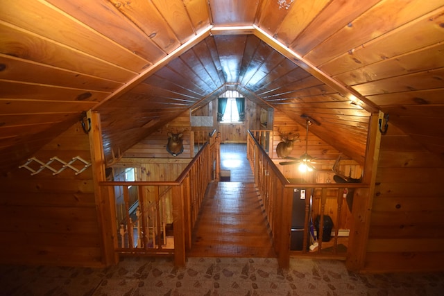 hall featuring wooden walls, hardwood / wood-style floors, wood ceiling, and vaulted ceiling