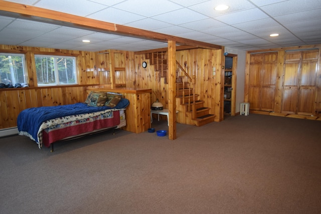 bedroom with carpet floors, a drop ceiling, and wood walls