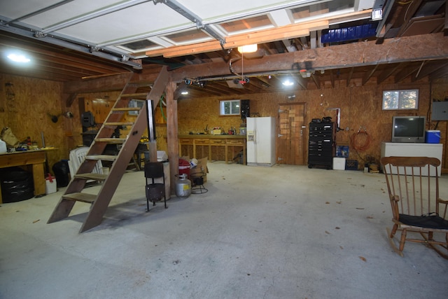 garage with a workshop area, a garage door opener, and white fridge with ice dispenser