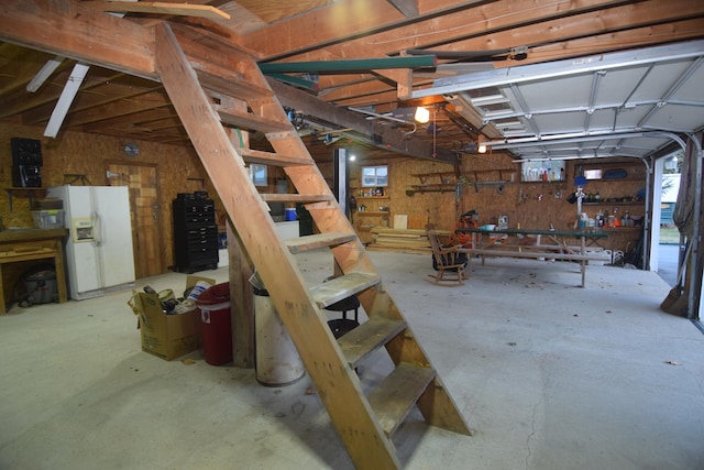 garage with a workshop area and white refrigerator with ice dispenser