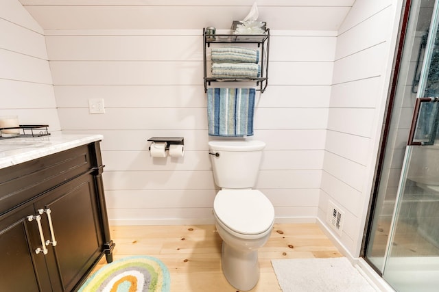 bathroom with vanity, lofted ceiling, wooden walls, hardwood / wood-style flooring, and a shower with shower door