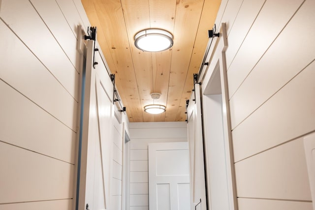 details featuring a barn door, wood walls, and wood ceiling