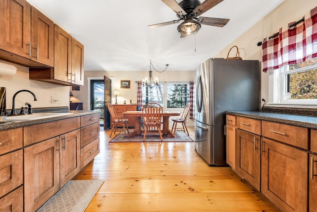 kitchen featuring stainless steel fridge, ceiling fan with notable chandelier, sink, decorative light fixtures, and light hardwood / wood-style floors