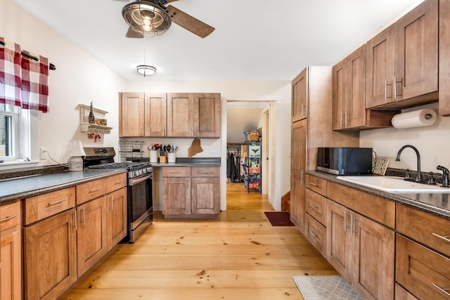 kitchen with ceiling fan, sink, stainless steel appliances, and light hardwood / wood-style floors