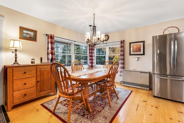 dining space with light hardwood / wood-style floors and a notable chandelier