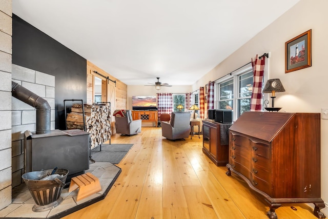 living room featuring ceiling fan, light wood-type flooring, and a wood stove