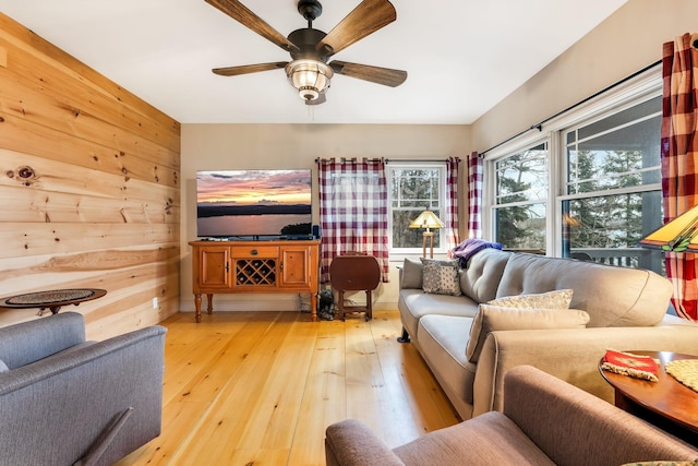 living room featuring hardwood / wood-style flooring, ceiling fan, and wood walls