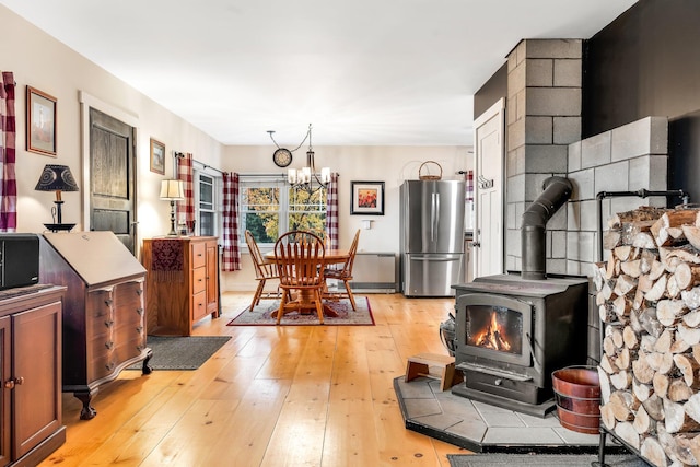 kitchen featuring stainless steel refrigerator, a chandelier, light wood-type flooring, and a wood stove