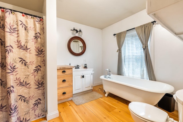 bathroom featuring vanity, hardwood / wood-style flooring, toilet, and a tub