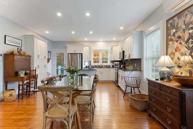11 Beacon Dr, Brunswick, ME 04011 - dining area featuring a wall unit AC, sink, and light hardwood / wood-style floors