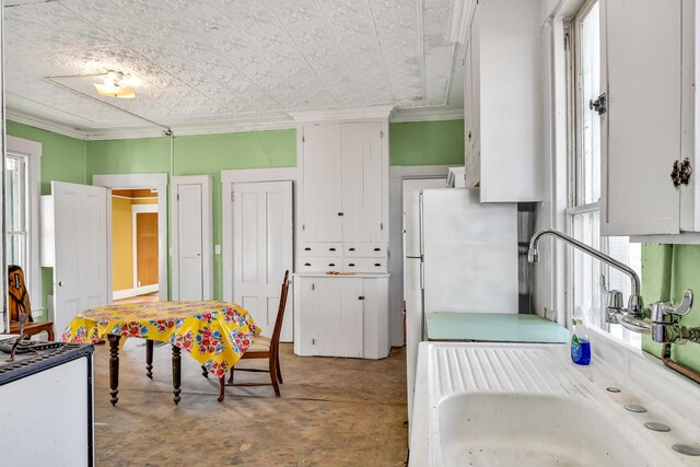 236 High St, Farmington, ME 04938 - kitchen with a sink, an ornate ceiling, ornamental molding, white cabinetry, and freestanding refrigerator