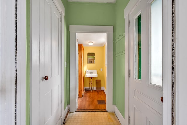 hall with light hardwood / wood-style floors and crown molding